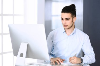 Modern ofiste bilgisayarla çalışan bir iş adamı. Arap erkek girişimcinin ya da iş yerindeki müdürün vesikalığı. İş konsepti