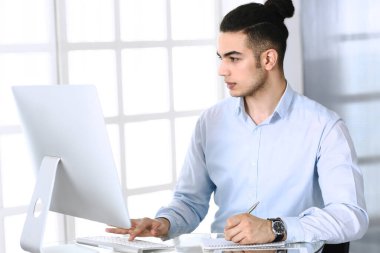 Modern ofiste bilgisayarla çalışan bir iş adamı. Arap erkek girişimcinin ya da iş yerindeki müdürün vesikalığı. İş konsepti