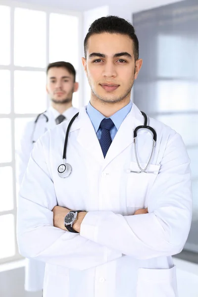 Arabische arts man staat met een blanke collega in het medisch kantoor of kliniek. Verscheidene artsen team, geneeskunde en gezondheidszorg concept — Stockfoto