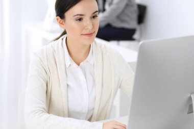 Ofiste bilgisayarla çalışan bir iş kadını, arka planda çalışan bir iş arkadaşı. Masada otururken avukatın ya da muhasebecinin vesikalığı.