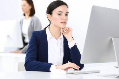 Ofiste bilgisayarla çalışan bir iş kadını, arka planda çalışan bir iş arkadaşı. Masada otururken avukatın ya da muhasebecinin vesikalığı.