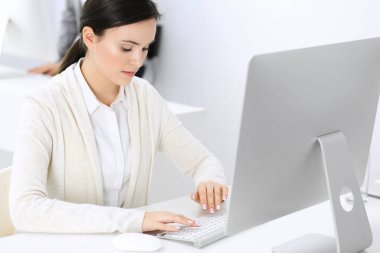 Ofiste bilgisayarla çalışan bir iş kadını, arka planda çalışan bir iş arkadaşı. Masada otururken avukatın ya da muhasebecinin vesikalığı.