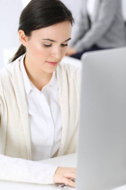 Ofiste bilgisayarla çalışan bir iş kadını, arka planda çalışan bir iş arkadaşı. Masada otururken avukatın ya da muhasebecinin vesikalığı.