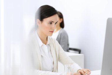 Ofiste bilgisayarla çalışan bir iş kadını, arka planda çalışan bir iş arkadaşı. Masada otururken avukatın ya da muhasebecinin vesikalığı.