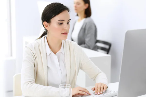 Mujer de negocios que trabaja con la computadora en la oficina, colega de fondo. Imagen de Abogado o Contador en el trabajo mientras está sentado en el escritorio —  Fotos de Stock