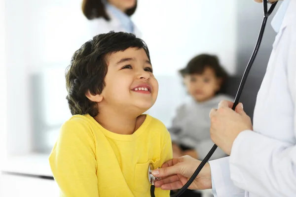 Médico examinando uma criança paciente por estetoscópio. Rapaz árabe bonito na consulta médica. Conceito de medicina e saúde — Fotografia de Stock