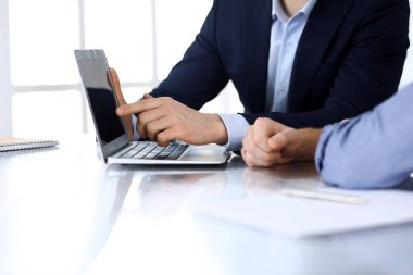 Modern ofiste birlikte çalışırken dizüstü bilgisayarı kullanan iş adamları. İş yerinde iş arkadaşı olan tanınmamış bir iş adamı ya da erkek girişimci. Takım çalışması ve ortaklık kavramı