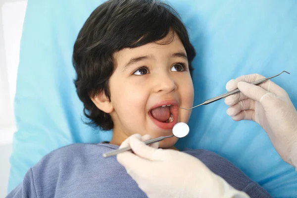 Menino árabe sentado na cadeira dentária com a boca aberta durante o check-up oral, enquanto médico. Consulta ao dentista. Conceito de medicina e estomatologia — Fotografia de Stock
