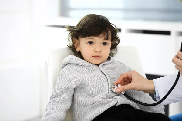 Médico examinando a un niño paciente por estetoscopio. Lindo chico árabe en la cita con el médico. Concepto de medicina y salud — Foto de Stock