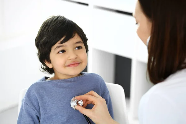 Médico examinando a un niño paciente por estetoscopio. Lindo chico árabe en la cita con el médico. Concepto de medicina y salud — Foto de Stock