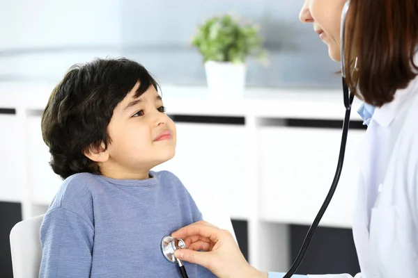 Médico examinando a un niño paciente por estetoscopio. Lindo chico árabe en la cita con el médico. Concepto de medicina y salud —  Fotos de Stock