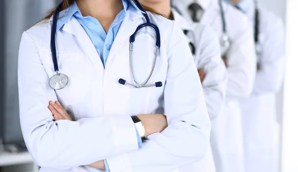 Bir grup modern doktor hastane ofisinde kollarını kavuşturmuş bir takım gibi duruyorlar. Doktorlar hastaları muayene etmeye ve yardım etmeye hazır. Tıbbi yardım, sağlık sigortası, en iyi hastalık tedavisi ve — Stok fotoğraf