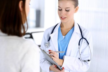 Muayene sırasında doktor ve hasta. Acil serviste dikilirken ilaç geçmişini dolduran bir doktor, portre çekimi. İlaç ve sağlık hizmetleri kavramı