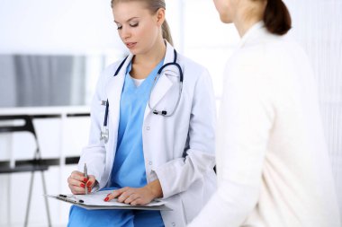 Muayene sırasında doktor ve hasta. Acil serviste portre çekimi yaparken ilaç geçmişini dolduran bir doktor. İlaç ve sağlık hizmetleri kavramı