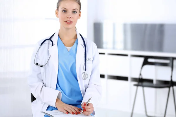 Läkare kvinna fylla upp medicinhistoria rekord när du sitter på akutmottagningen. Läkare på jobbet, studioporträtt. Medicin och hälsovård — Stockfoto
