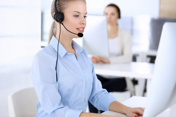 呼叫中心办公室漂亮的金发女人用电脑和耳机在网上咨询客户。作为客户服务职业的操作员群体。商人概念 — 图库照片