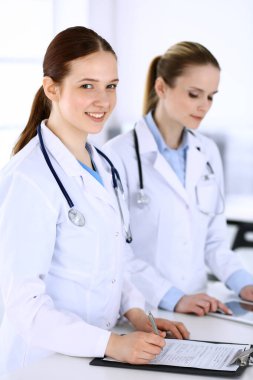 Hastanede çalışan bir grup doktor. Doktor resepsiyonda beklerken tıbbi belge ya da reçete dolduruyor. Tıp ve sağlık hizmetleri kavramındaki veriler