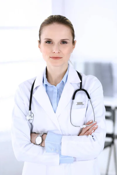 Dottoressa donna colpita alla testa al lavoro in ospedale. Medico in piedi dritto e sorridente, ritratto in studio. Medicina e concetto di assistenza sanitaria — Foto Stock