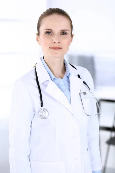 Una doctora disparando en el trabajo en el hospital. Médico de pie recto y sonriente, retrato de estudio. Concepto de medicina y salud — Foto de Stock
