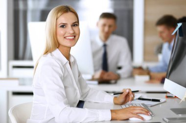 Modern ofisteki işyerinde bilgisayar kullanan bir iş kadını. Sekreter ya da kadın avukat gülümsüyor ve mutlu görünüyor. Zevk ve başarı için çalışmak