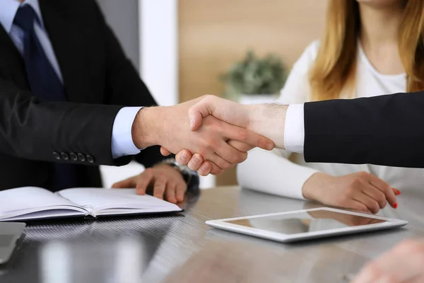 Zakenman schudt handen met zijn collega of partner boven het glazen bureau in modern kantoor, close-up. Onbekende zakenmensen bij een ontmoeting. Teamwork, partnerschap en handdruk concept — Stockfoto