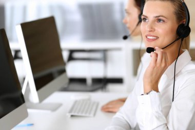 Merkezi ara. İnternette müşterilere danışırken kulaklık kullanan mutlu ve heyecanlı bir iş kadını. Müşteri hizmetleri ofisi ya da tele pazarlama bölümü. İşte gülümseyen operatörler grubu
