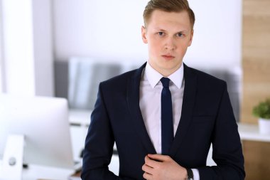 Ofisteki kameraya bakıp duran neşeli iş adamı. Genç ve başarılı girişimcinin vesikalığı. İş konsepti