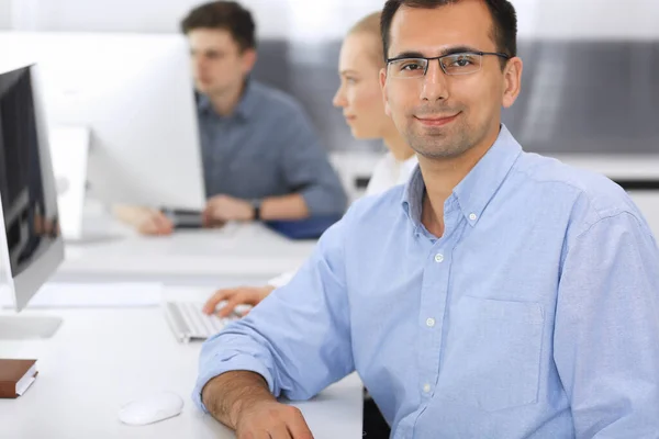 Business people working together in modern office. Focus at happy smiling adult businessman or entrepreneur using pc computer. Teamwork and partnership concept. Casual dress style