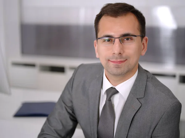 Un hombre de negocios en una reunión en una oficina moderna. Empresario sentado a la mesa con sus colegas. Trabajo en equipo y concepto de asociación. Blazer gris se adapta a gerente sonriente feliz —  Fotos de Stock