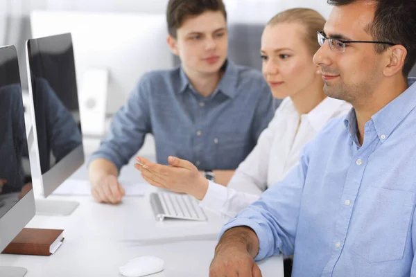 Business people working together in modern office. Focus at happy smiling adult businessman or entrepreneur using pc computer. Teamwork and partnership concept. Casual dress style Stock Image