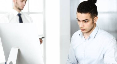 İşadamı modern ofiste bilgisayarla çalışıyor. Arap erkek girişimcinin iş yerindeki portresi. İş konsepti