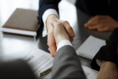 Bilinmeyen işadamı, modern ofiste iş arkadaşı ya da ortağıyla el sıkışıyor. Toplantıda iş adamları grubu