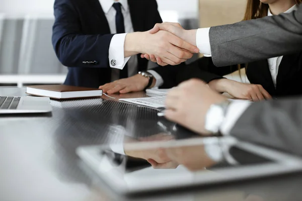 Bilinmeyen işadamı, modern ofiste iş arkadaşı ya da ortağıyla el sıkışıyor. Toplantıda iş adamları grubu