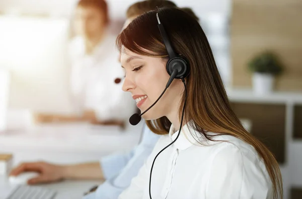 Asian woman working at customer service office. Business concept. Group of diverse operators at work in sunny call center.