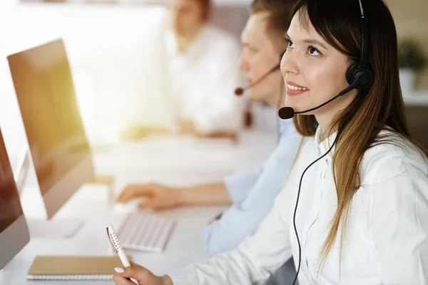 Asian woman working at customer service office. Business concept. Group of diverse operators at work in sunny call center.