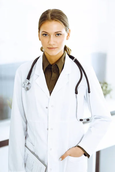 Mujer-médico de pie y mirando a la cámara. Servicio médico perfecto en la clínica — Foto de Stock