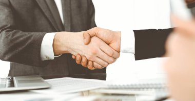 Bilinmeyen çeşitli iş adamları ofis masasındaki toplantıyı bitirmek için el sıkışıyorlar, yakın plan. El sıkışma kavramı