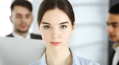 Modern ofisin arka planında iş kadını ve çeşitli iş adamları var. Çok ırklı takım çalışması ve iş konsepti