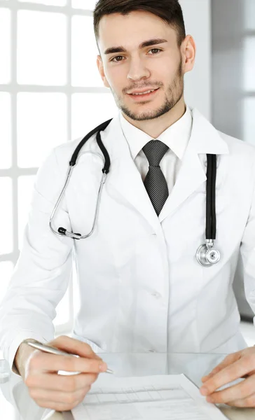 Doktor adam klinikteki cam masada otururken ilaç kayıtlarını dolduruyor. Tıp ve sağlık hizmetleri kavramı — Stok fotoğraf