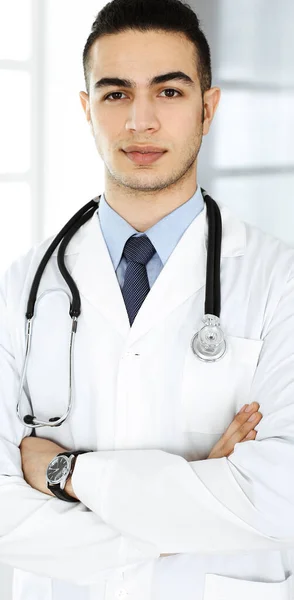 O médico árabe está de pé com os braços cruzados na clínica. Conceito de medicina e saúde — Fotografia de Stock