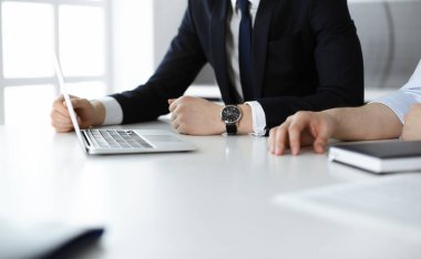 Bilinmeyen iş adamları modern ofisteki masada dizüstü bilgisayar kullanıyorlar. İş adamı ya da erkek girişimci meslektaşı ile birlikte çalışıyor. Takım çalışması ve ortaklık kavramı