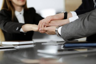 Bilinmeyen iş adamları modern ofiste el ele tutuşuyor. İş adamları ve kadınlar elleriyle bir takım olarak daire çiziyorlar, yakın plan.