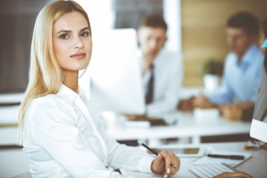 Modern ofisteki işyerinde bilgisayar kullanan bir iş kadını. Sekreter ya da kadın avukat gülümsüyor ve mutlu görünüyor. Zevk ve başarı için çalışmak