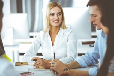 Bir grup iş adamı toplantıda soruları tartışıyor. Ofis görüşmelerinde iş arkadaşına gülümseyen sarışın iş kadınının vesikalığı. Şirket işgalinde takım çalışması ve işbirliği