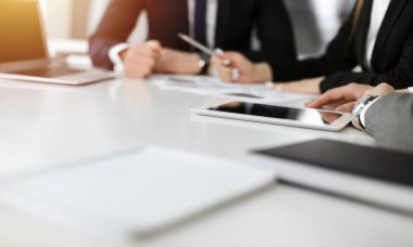 Bilinmeyen iş adamları ve kadınlar oturuyor, dizüstü bilgisayar kullanıyorlar ve güneşli ofiste soruları tartışıyorlar, yakın plan. Başarı konsepti