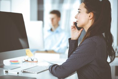 Modern ofisteki işyerinde bilgisayar kullanan bir iş kadını. Esmer sekreter ya da kadın avukat gülümsüyor ve mutlu görünüyor. Zevk ve başarı için çalışmak