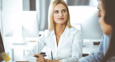 Bir grup iş adamı toplantıda soruları tartışıyor. Ofis görüşmelerinde iş arkadaşına gülümseyen sarışın iş kadınının vesikalığı. Şirket işgalinde takım çalışması ve işbirliği