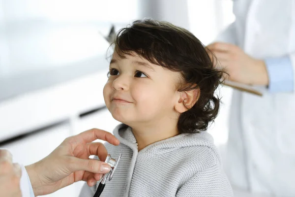 Vrouwendokter die een kindpatiënt onderzoekt met stethoscoop. Leuke Arabische peuter op afspraak bij de dokter. Geneesmiddelenconcept — Stockfoto