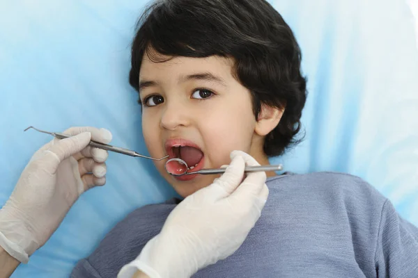在与医生进行口试时，坐在牙椅上张开嘴的可爱的阿拉伯男孩。去看牙医口腔学概念 — 图库照片