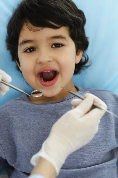 Menino árabe sentado na cadeira dentária com a boca aberta durante o check-up oral com o médico dentista. Conceito de estomatologia — Fotografia de Stock